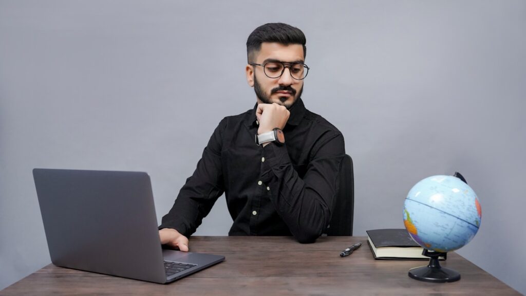 a man sitting at a desk with a laptop and a globe