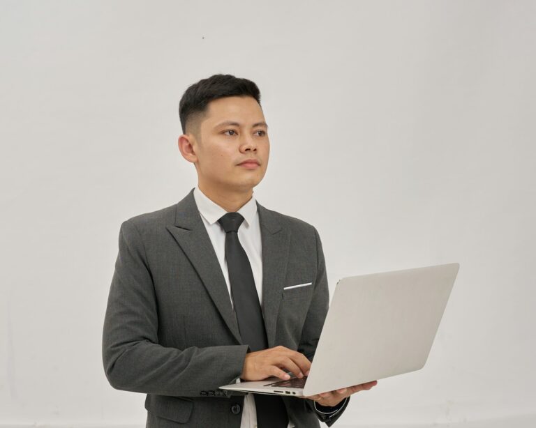 A businessman is holding a laptop and looking up.