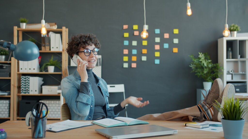 Woman talking on phone at desk with feet up