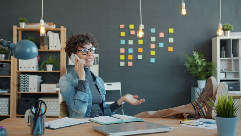 Woman talking on phone at desk with feet up